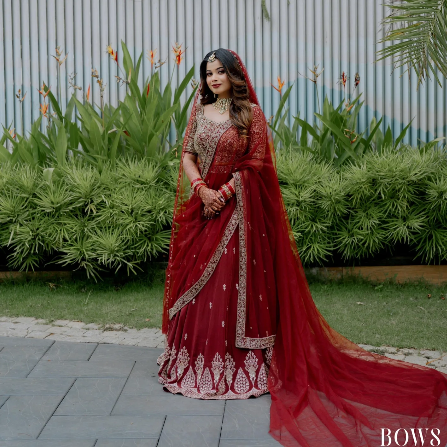 Bride in red and gold embroidered lehenga, photographed outdoors